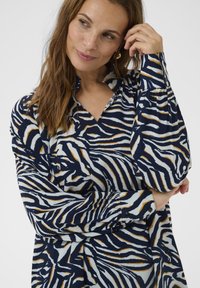 Langærmet skjorte med et navy, hvidt og orange zebra-stribe mønster, med V-hals og knapmanchetter. Blødt stof med en afslappet pasform.