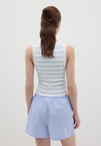 Gestreifter Tanktop in Hellblau und Weiß, kombiniert mit hellblauen gestreiften Shorts. Fokus auf strapazierfähige Stoffe und elastischem Bund.
