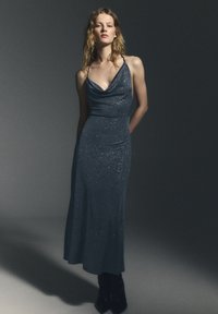 Abito da sera blu scuro con collo a scialle, silhouette aderente, coperto da sottili glitter, con gonna lunga e tasca laterale.