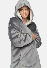 Couverture capuche en molleton gris doux avec un doublure en Sherpa blanche, dotée d'une grande poche avant et d'un design décontracté et surdimensionné.