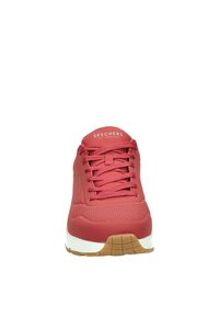 Sneaker sintetica rossa con superficie testurizzata, dotata di lacci piatti e di una suola intermedia bianca, accentuata da una suola in gomma marrone. Logo del marchio sulla linguetta.