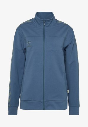 Blå zip-up jakke lavet af blødt materiale, med høj krave, ribbede manchetter og kontraststribede detaljer på ærmerne.