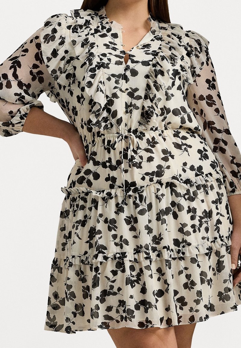 Blommig klänning med volang på halsringning och ärmar, tillverkad av lättviktsmaterial, i creme med svarta lövmönster och justerbart snöre i midjan.