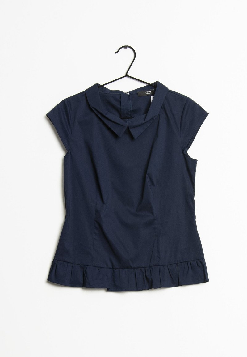 Blouse bleu marine à manches courtes avec un col pointu et un ourlet volanté suspendue sur un cintre noir sur fond blanc.