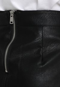 Gonna nera in pelle sintetica con una texture liscia, dotata di una cerniera metallica sul lato e linee pulite per un look su misura.