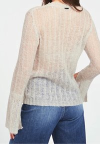 Lightweight knit sweater in beige, featuring vertical stripes and flared sleeves, with a textured finish and subtle color gradient.