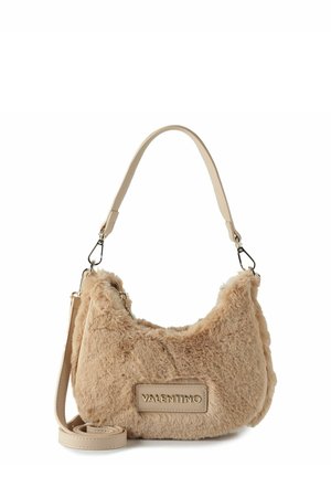 Beige Kunstpelztasche mit geschwungener Form, abnehmbarem Ledertragegurt und einem auffälligen Logo-Plakette an der Seite. Silberne Hardware-Details.