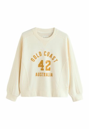 Sudadera color crema con tejido texturizado, mangas raglán y texto impreso: "GOLD COAST 42 AUSTRALIA" en dorado.