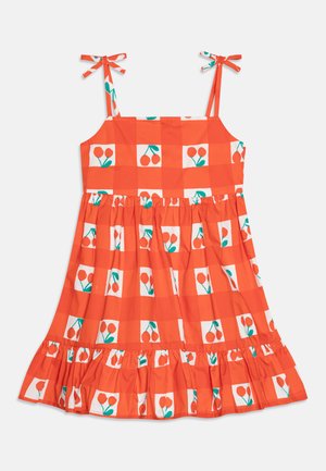 Punainen ja valkoinen ruudullinen mekko kirsikka- ja lehpäkuvioilla, jossa on spagettiolkaimet ja nauhaviritelmät sekä röyhelöhelma. Puuvillamateriaalia.