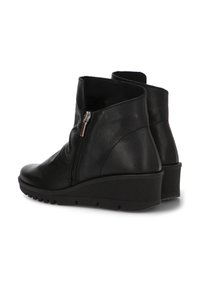 Botas de tobillo de cuero negro con tacón de cuña, cierre de cremallera, textura suave y puntera redonda para mayor comodidad.