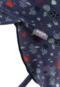 Navy swim cap with ocean-themed print; features turtles, crabs, coral, and fish. Smooth texture with contrasting edge detailing.