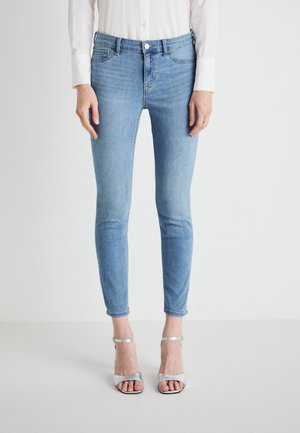 Vaaleansiniset slim fit -farkut, joissa on etutaskut, nappikiinnitys ja sileä pinta, yhdistettynä hopeisiin remmisandaaleihin.