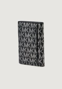 Portafoglio compatto nero caratterizzato da un motivo ripetuto con il monogramma "MK" in argento, piegato con cuciture visibili lungo i bordi.