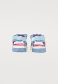 Des sandales bleues avec deux brides réglables, dotées d'une semelle intérieure rose et d'une semelle extérieure blanche. Matériau lisse avec une finition brillante.
