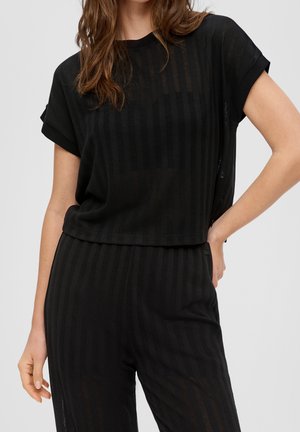 Sort top med korte ærmer og løs pasform, med et lodret stribet mønster og rund halsudskæring. Båret sammen med matchende sorte bukser.