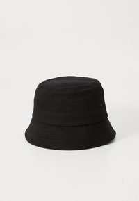 Pălărie de bumbac neagră în stil bucket, cu o coronă rotundă și o margine lată, care se înclină în jos. Textură netedă, fără modele sau accente vizibile.