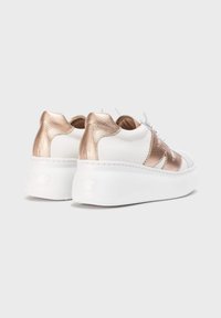 Zapatillas de deporte blancas de cuero con un acento texturizado en oro rosa. Suela blanca elevada, forma redondeada y cordones en contraste.