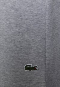 Gray cotton fabric with a textured knit, featuring a small green and white crocodile logo on the lower left side.