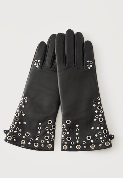 Gants en cuir noir avec œillets métalliques argentés et clous décorant les poignets et les zones des doigts, posés à plat sur un fond blanc.