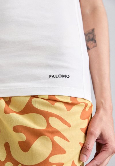 White cotton t-shirt featuring a black "PALOMO" label at the hem, paired with yellow shorts displaying an orange abstract pattern.