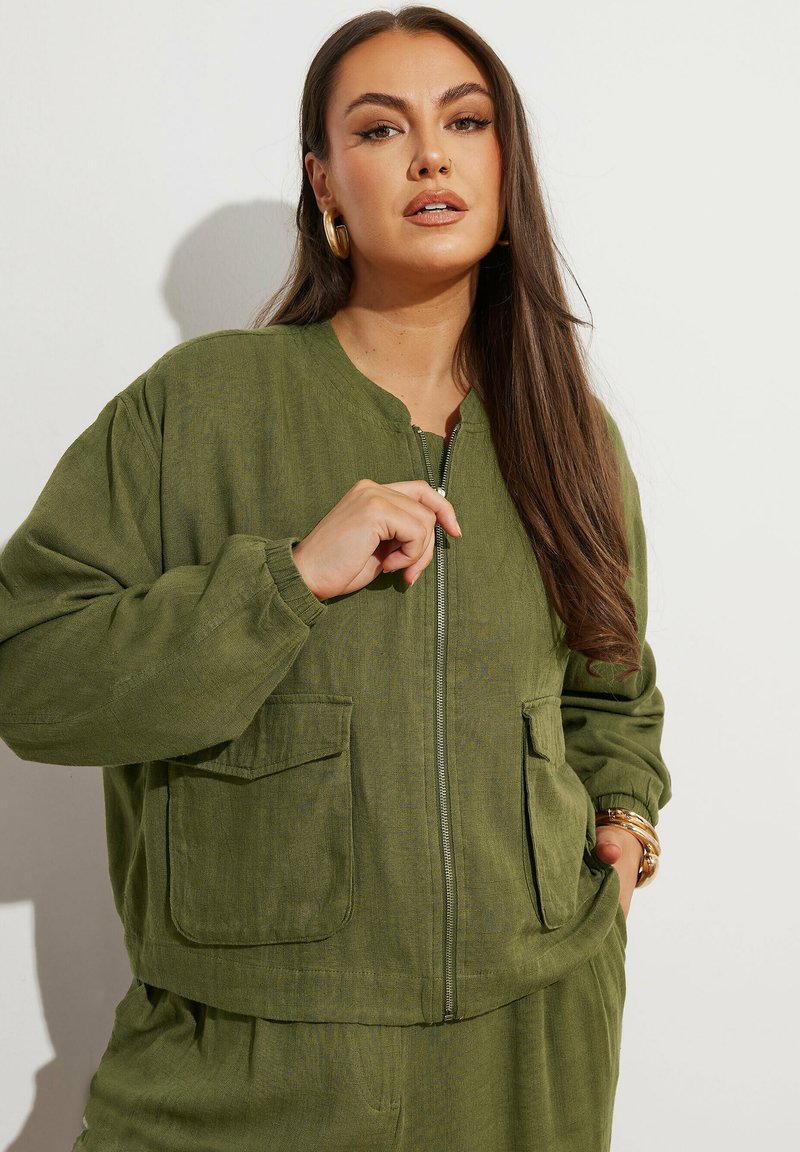Giacca bomber verde oliva con zip frontale, scollatura rotonda e due tasche anteriori. Realizzata in tessuto leggero e dalla texture interessante.