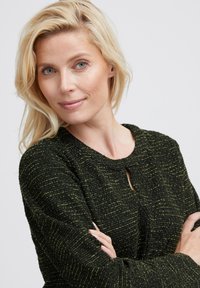 Czarna i zielona teksturowana dzianinowa odzież z okrągłym dekoltem i detalem w postaci keyhole, charakteryzująca się miękkim materiałem i luźnym krojem.