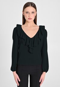 Blusa nera con profondo scollo a V, dettagli in volant sul davanti e sulle spalle, e maniche lunghe a sbuffo, realizzata in un tessuto morbido e liscio.