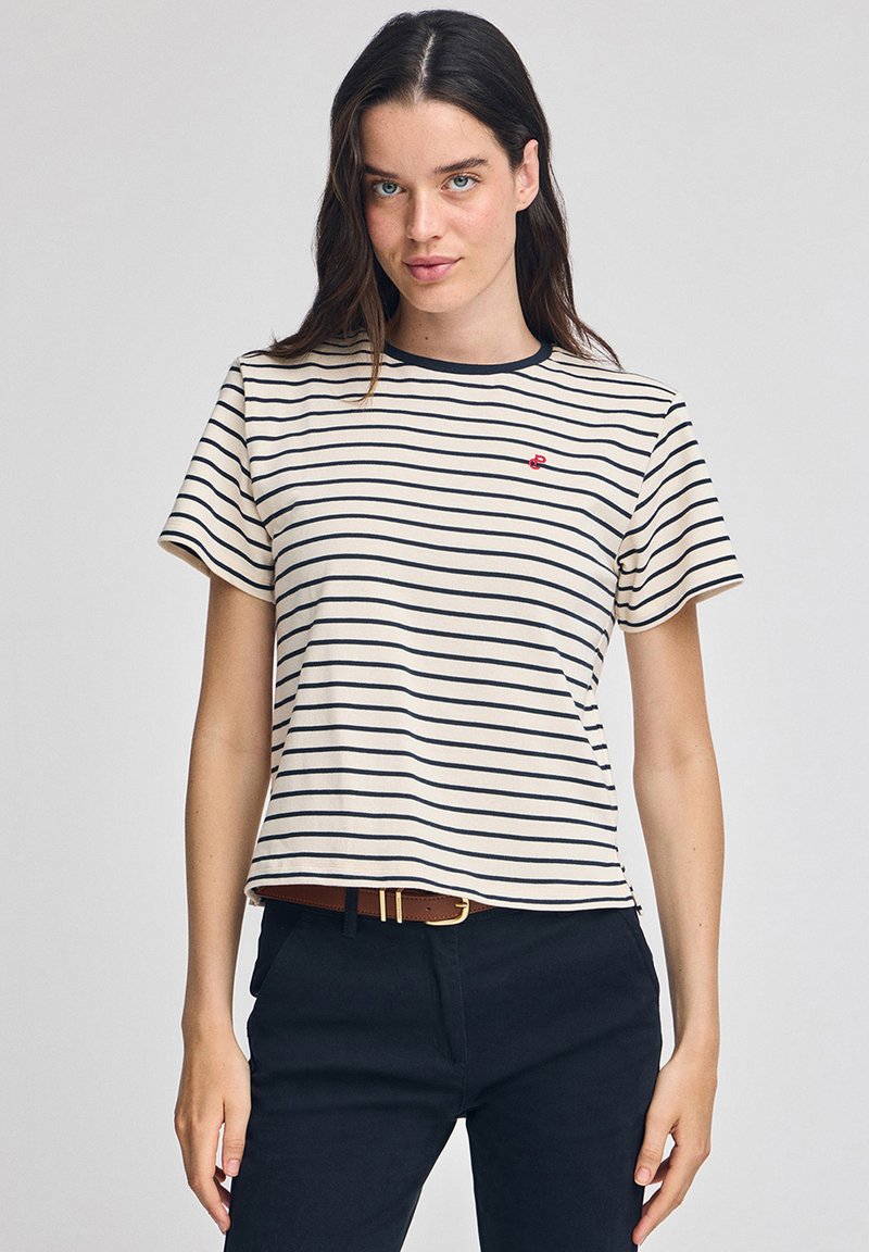 Randig t-shirt i beige med marinblå ränder, rund halsringning, korta ärmar och liten röd logotyp på vänster bröst. Mjukt bomullsmaterial.