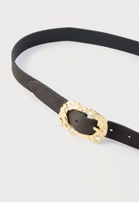 Sort bælte i ruskind med en tekstureret guldlås med klare ædelsten. Spændet er rundt og har et udsmykket design.