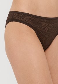 Biquíni castanho de renda com um padrão de folhas texturizado, apresentando um design de cintura baixa e bordas sem costura para conforto.