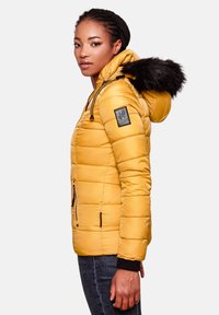 Geel gewatteerde pufferjack met een met bont afgewerkte capuchon, ritszakken en een zwart accentpatch op de mouw. Glad, glanzend materiaal.