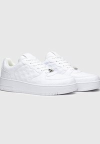 Sneakers bianchi con materiale testurizzato che presenta un motivo. Forma arrotondata, suola spessa e design con lacci con dettagli in metallo.