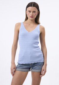 Top aderente azzurro chiaro con un design a coste testurizzato, scollatura a V profonda e orlo scallop. Indossato con pantaloni denim, mette in risalto uno stile casual.