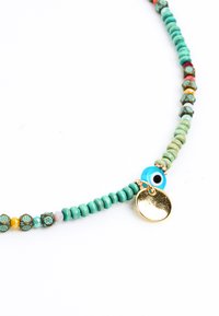 Collana di perline colorate con perline turchesi, dorate e decorate, con un prominente ciondolo a forma di occhio blu e un luccicante pendente dorato.