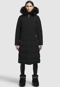 Černá prošívaná bunda s dlouhým designem, s kapucí lemovanou kožešinou, zipovým předním zapínáním a bočními kapsami. Ukončena hladkou texturou.