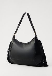 Borsa a mano in pelle nera con una silhouette arrotondata, caratterizzata da dettagli texturizzati e frange su un lato. Tracolla regolabile con hardware dorato.