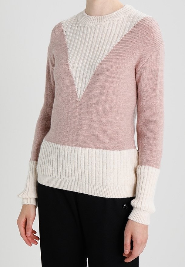 Pull en maille avec un design bloc de couleur rose et crème. Présente une texture côtelée sur les poignets et l'ourlet, ainsi qu'un motif en forme de V sur la poitrine.