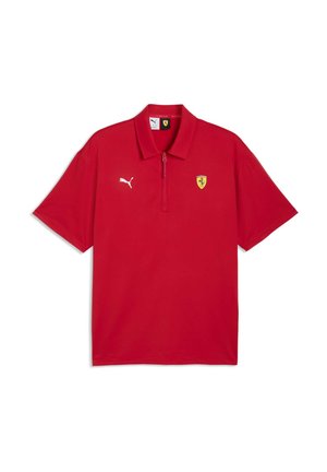 Czerwona koszulka polo wykonana z gładkiej tkaniny, z kołnierzem na zamek, białym logo Puma i żółtym emblematem Ferrari. Krótkie rękawy i luźny fason.