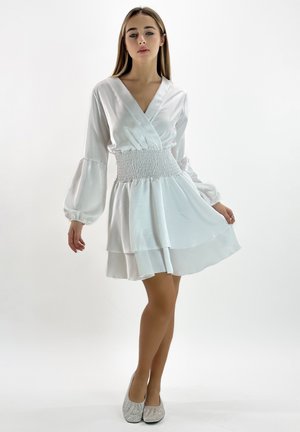 Witte satijnen jurk met een overlappend voorpand, geplooide taille en gelaagde rok. Lange puffmouwen en een gladde textuur aanvullen het elegante ontwerp.