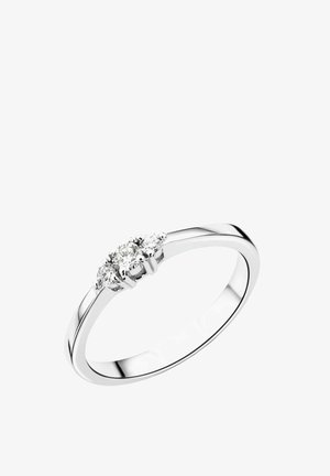 Kolme kivi ring, millel on poleeritud hõbedane bänd, kus on klastrisse paigutatud kolm ümmargust selget teemanti.