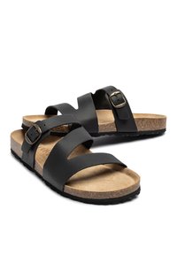 Black leather sandals with two straps featuring a buckle, cork footbed with a textured brown surface, and a black rubber sole.