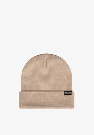Beige gebreide muts met een opgerolde rand, gemaakt van zacht materiaal. Heeft een klein merklabel aan de zijkant.