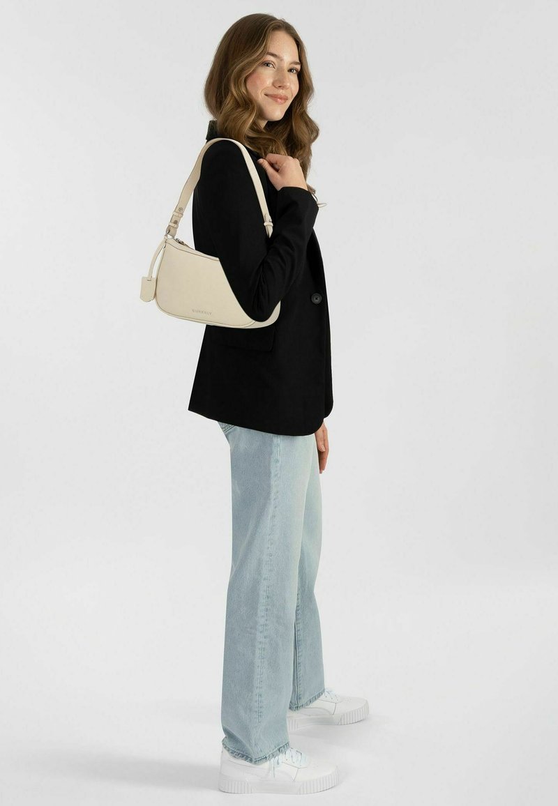 Borsa a tracolla in morbida pelle crema, dalla forma curvilinea, con tracolla regolabile, dotata di chiusura con zip e discreta marca sul lato.