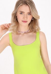 Top verde lime strălucitor, cu decolteu rotund, țesătură texturată și bretele subțiri. Design simplu, ajustat, fără modele suplimentare.