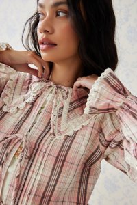 Top a quadri rosa e crema con maniche a sbuffo, dettagli in pizzo e chiusura a fiocco. Tessuto strutturato con un design a strati.