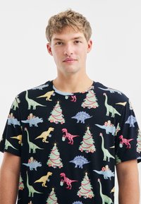 Zwart T-shirt met korte mouwen, bedrukt met kleurrijke dinosaurussen en kerstbomen, met verschillende texturen en levendige kleuren, rond neklijn ontwerp.