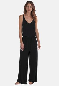Sort ærmeløs jumpsuit med V-hals, brede bukser og elastisk talje. Blødt stof med en glat overflade, minimalistisk design.