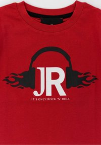 Červené bavlněné tričko s grafikou černých sluchátek s plameny a textem "JR" v bílé barvě pod frází "JDE JEN O ROCK 'N' ROLL."