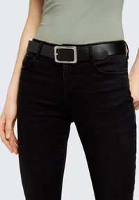 Musta nahkavöö hõbedase ristküliku vormis pandlaga. Vöö on sileda tekstuuriga ja sobib mustade denim pükste juurde.