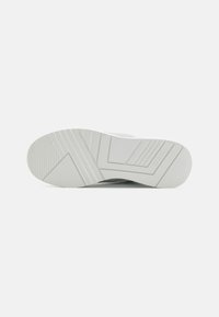 Sole di sneaker bianca in gomma testurizzata, con scanalature angolari e stampa del logo. Finitura liscia con elementi di design a contrasto.